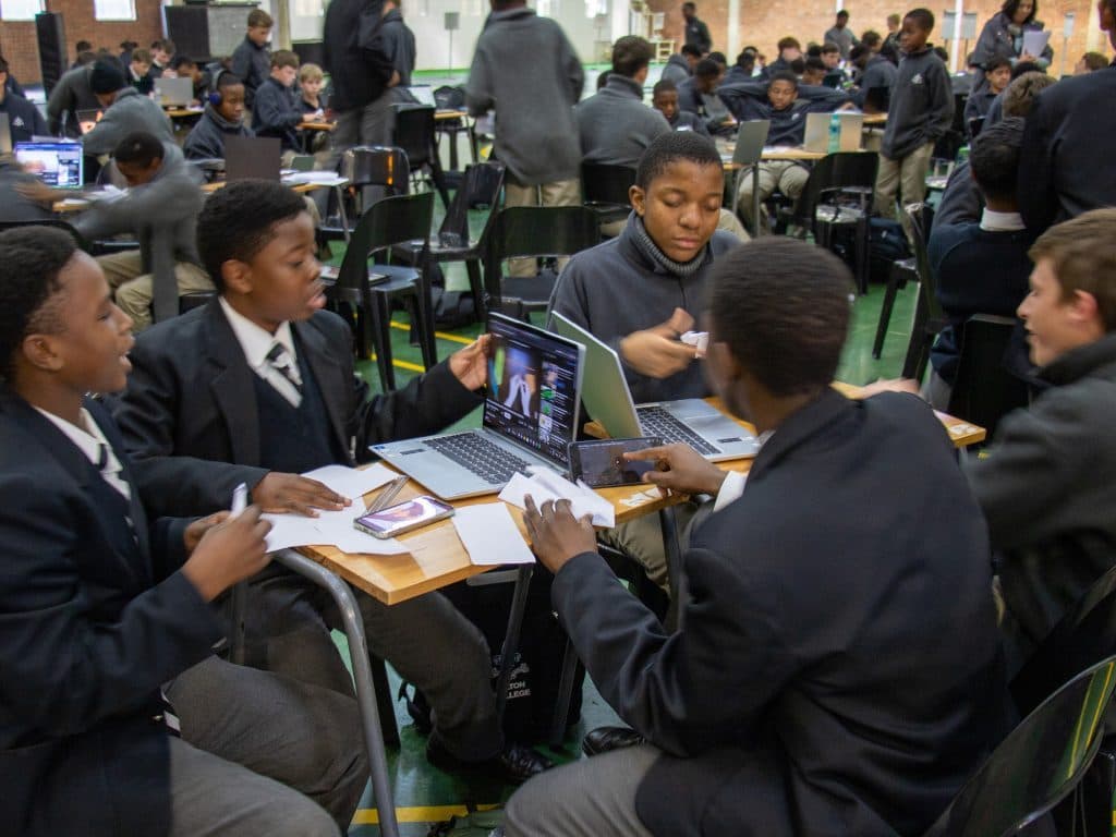 Students collaborating with laptops in a South African classroom