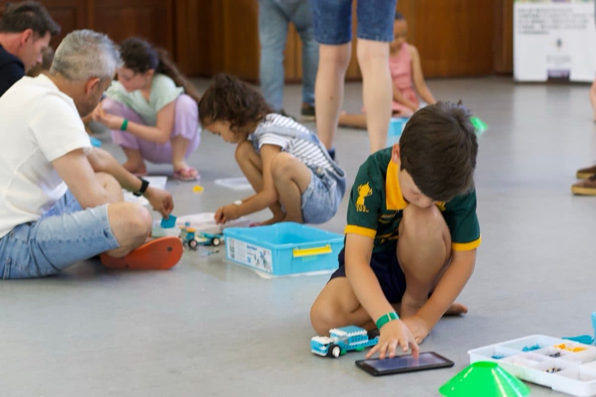 Boy in school uniform coding a robot with a tablet at an event