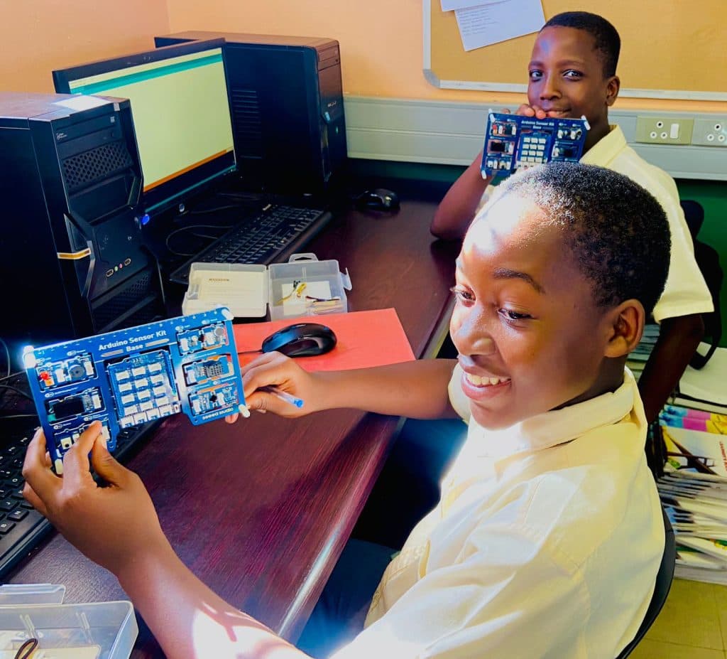 Kids smiling while holding the Arduino Sensor Kit Base board
