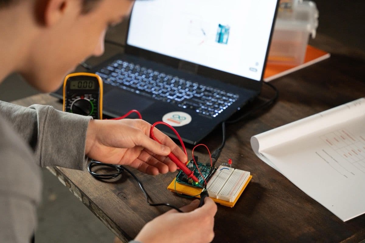Teen working on the Arduino Student Kit with workbook and laptop open