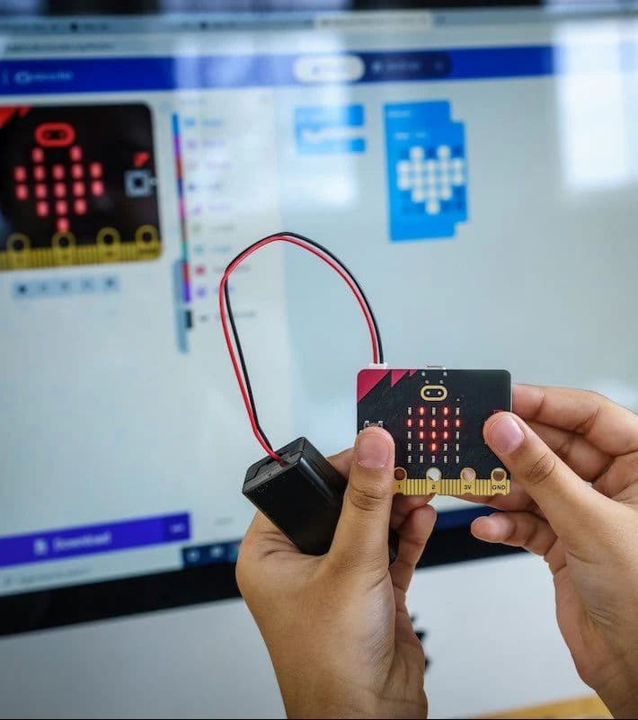 Learner holding a micro:bit with battery holder attached