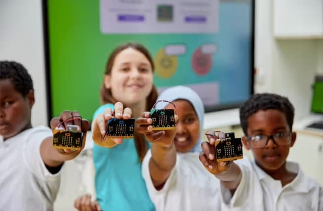 Two children holding micro:bit boards and smiling