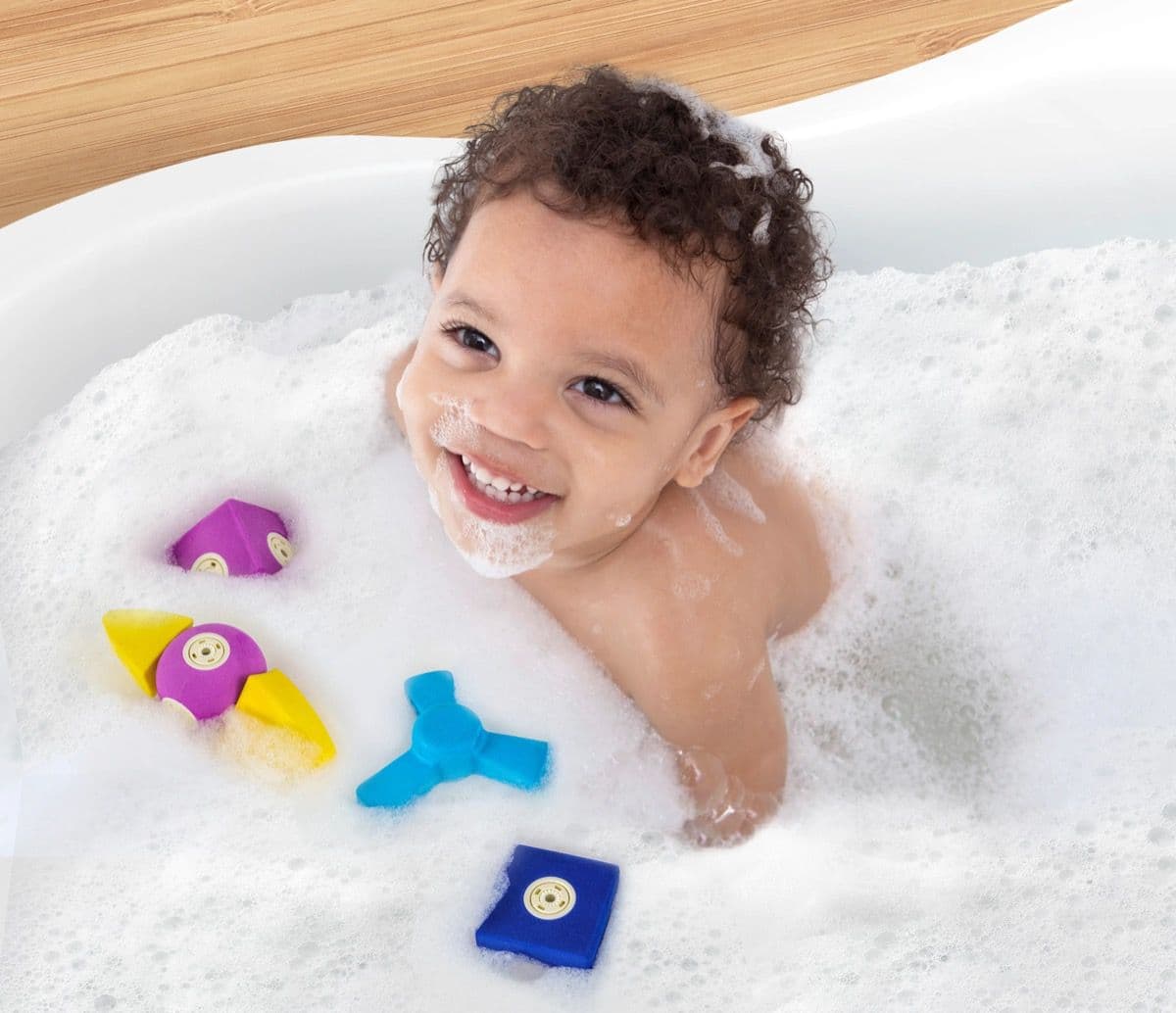 Child laughing and playing with Blockaroo magnetic foam blocks in the bath