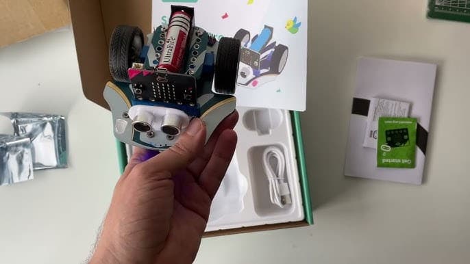 Hand holding the assembled Cutebot Pro above its packaging box