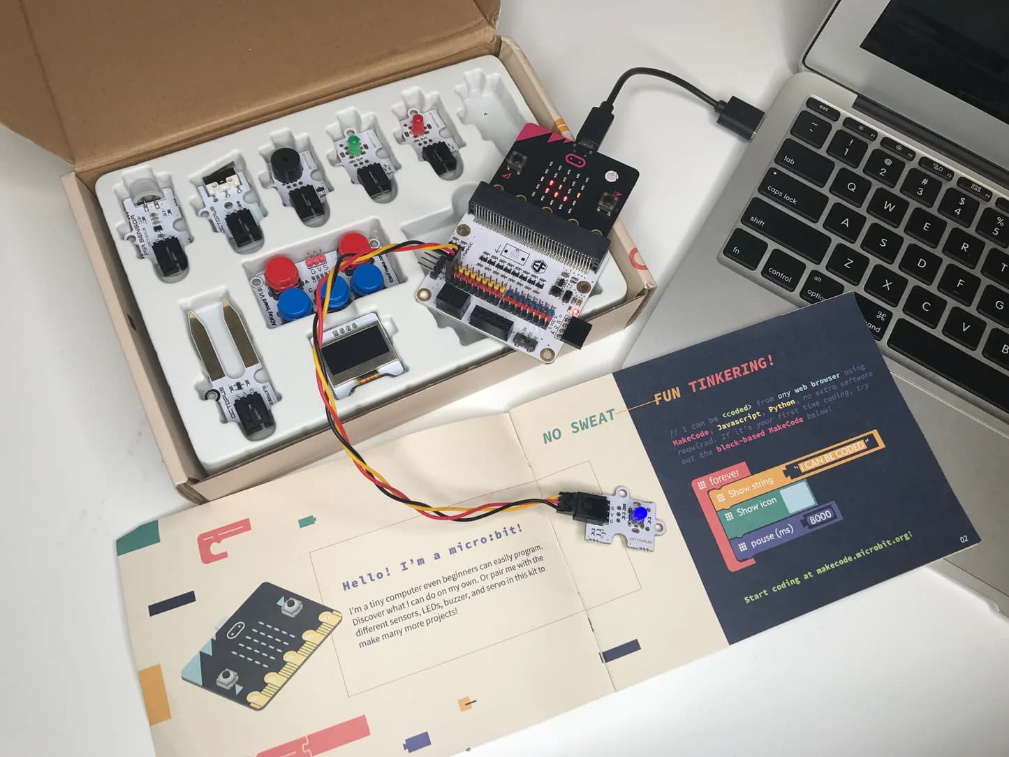 Tinker Kit display box open with the manual visible and micro:bit connected to a laptop
