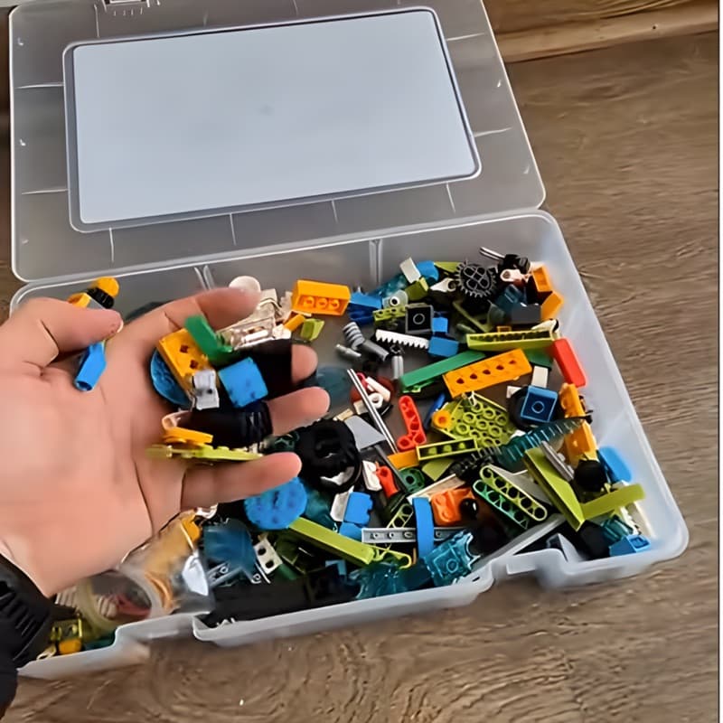 Hand holding building blocks above a box filled with more pieces