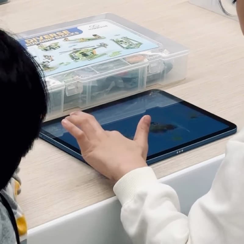 Child using the Makerzoid app on a tablet with the product box in front