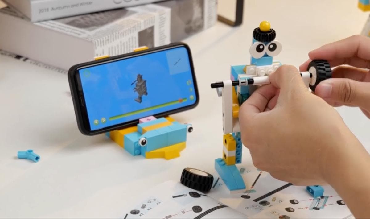 Child building a robot with phone app instructions visible