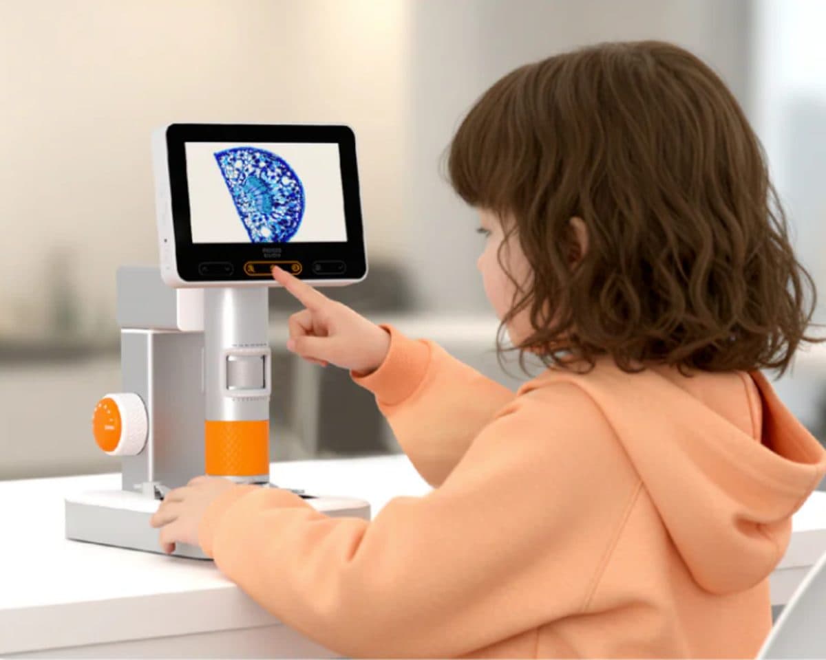 Young girl pointing excitedly at the MatataStudio microscope screen showing a magnified specimen