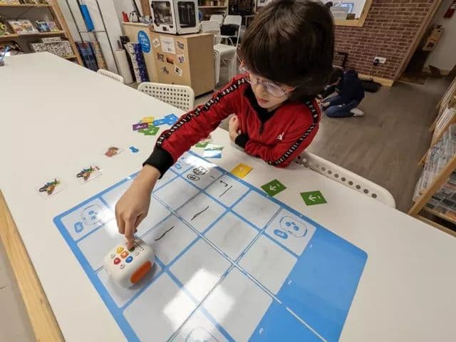 Boy pressing command buttons on Tale-Bot Pro robot during a lesson