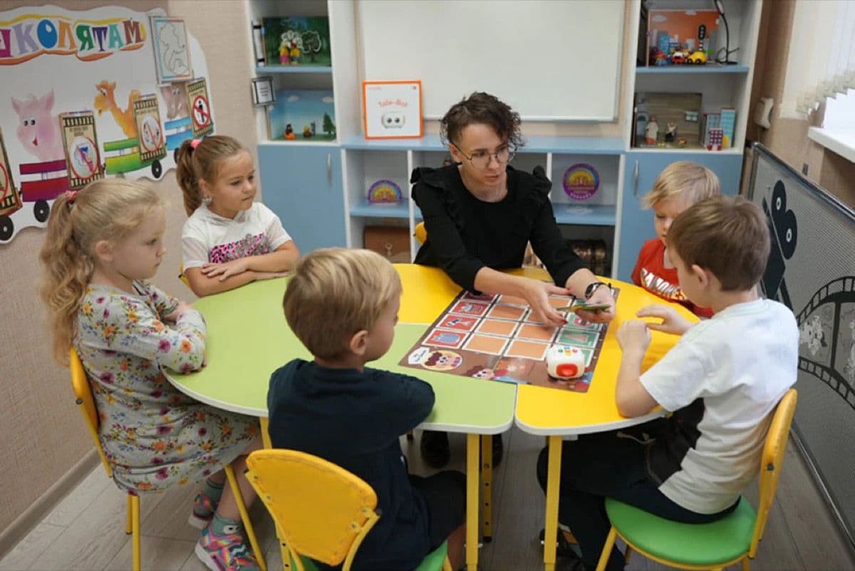 Teacher handing out activity cards to learners before a coding lesson