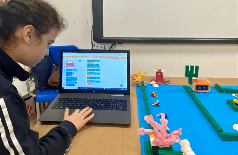 Child coding on laptop with VinciBot on a pathway