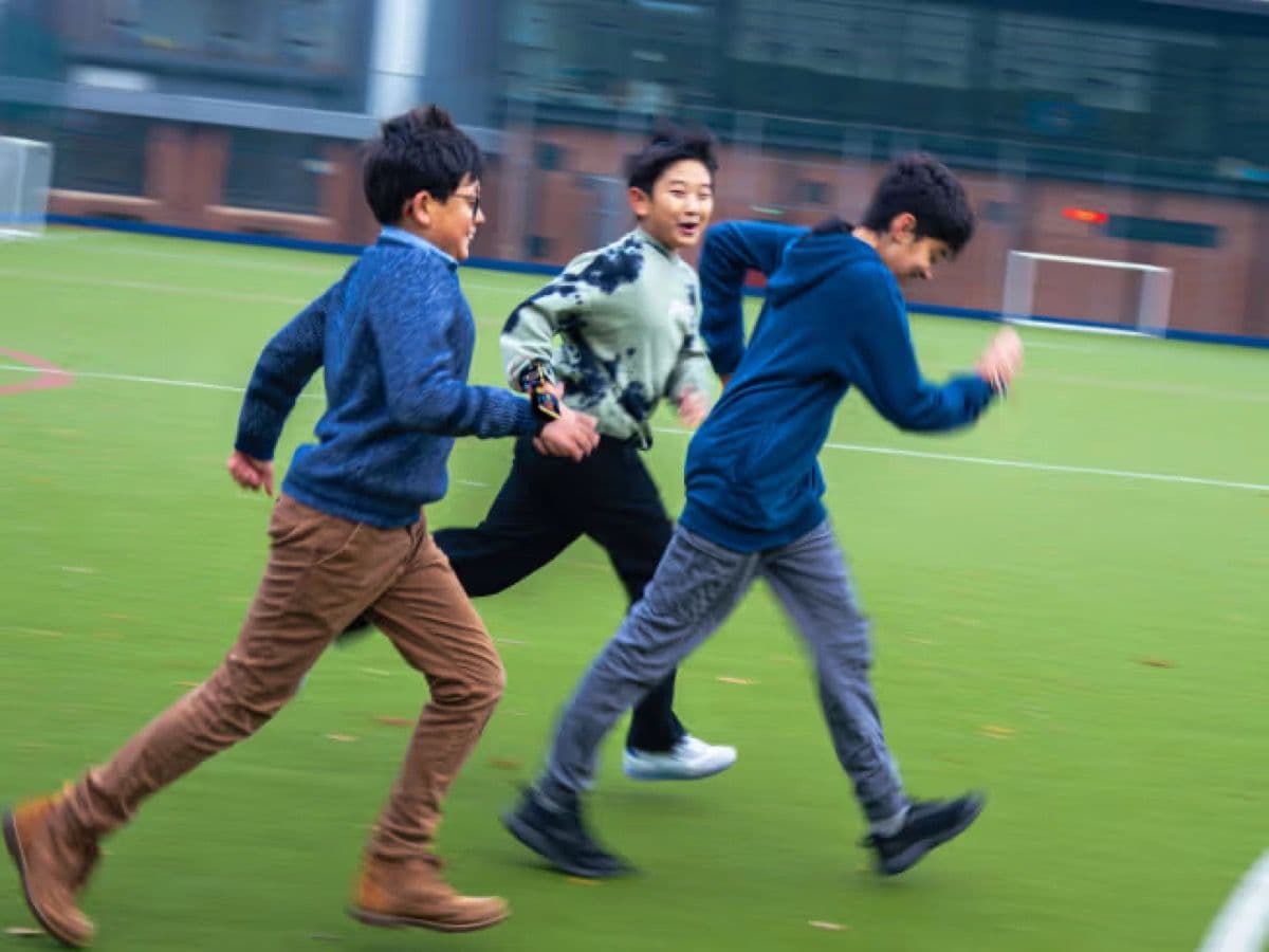 Children running in a group with BBC micro:bit wearables strapped to their wrists