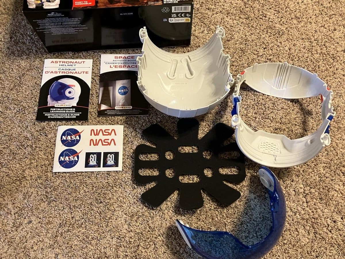 All helmet components laid out including foam pad, sticker sheet and learning guide