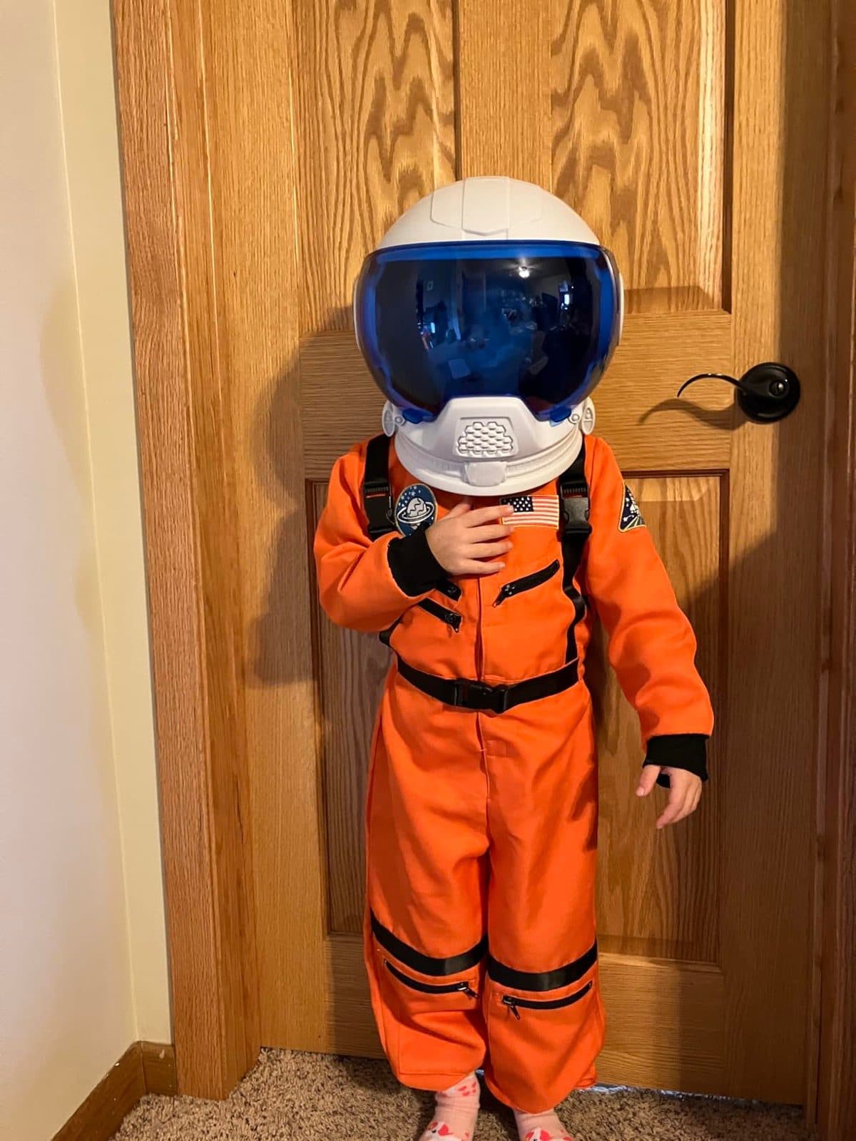 Child in orange astronaut suit wearing the NASA helmet