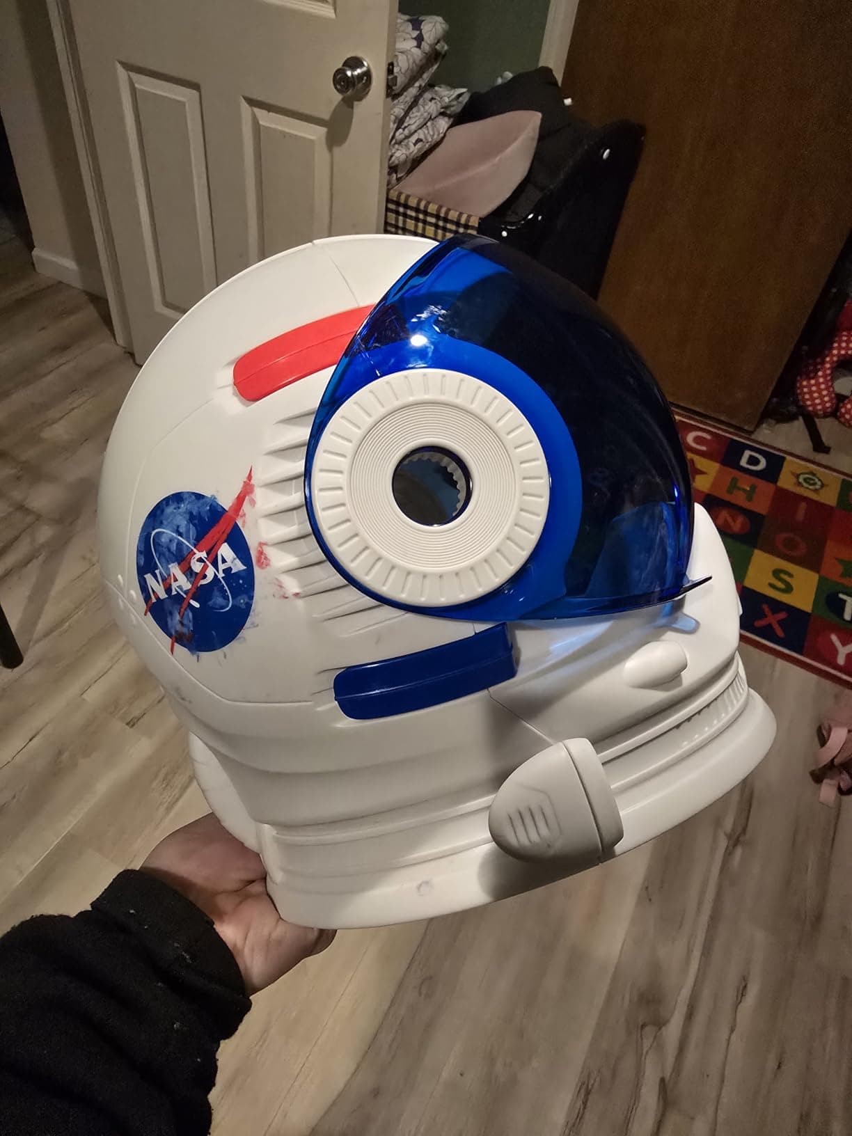 Hand holding the assembled NASA astronaut helmet with visor open