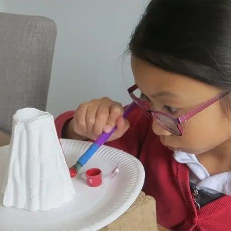 Girl carefully painting her volcano