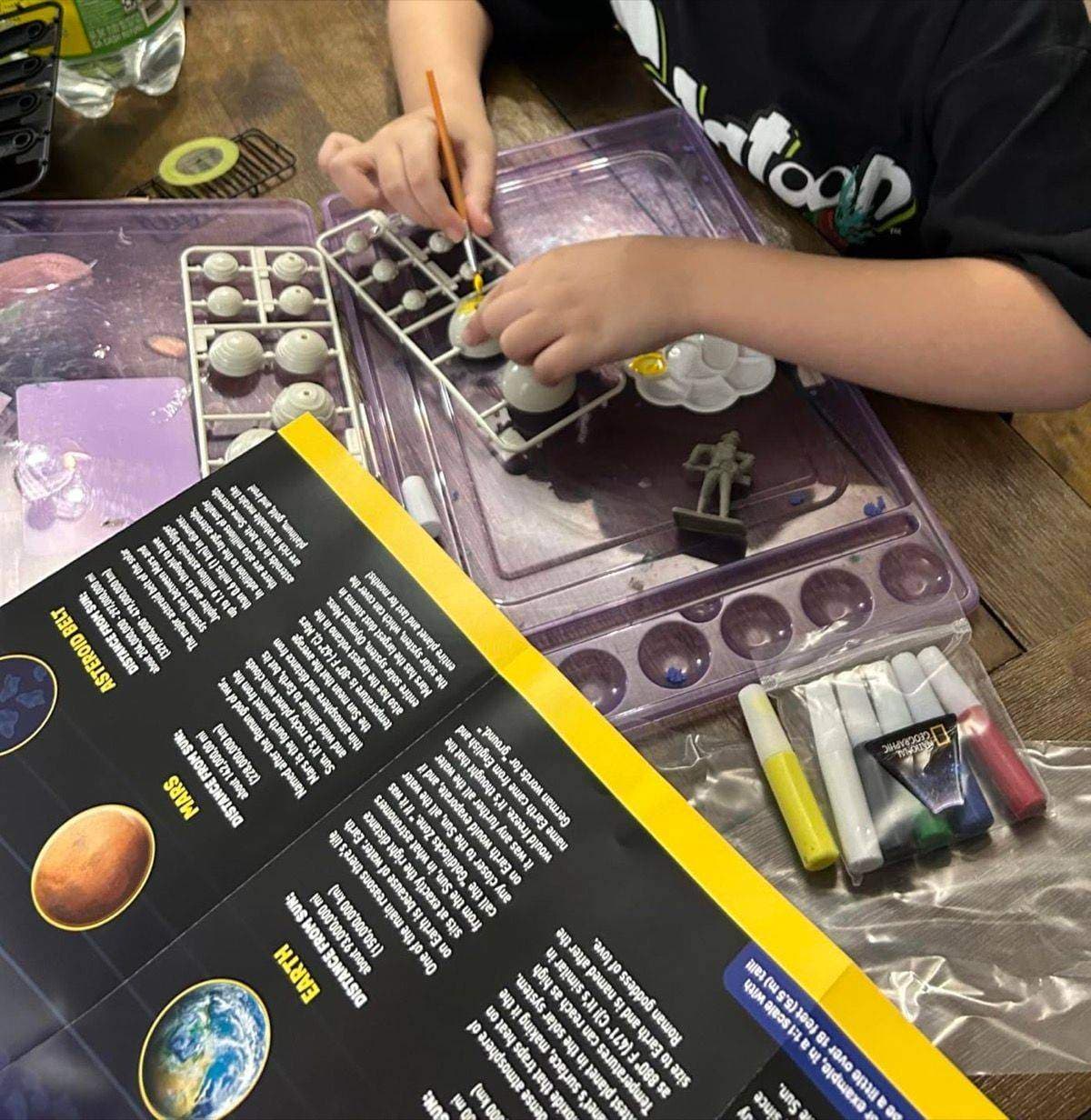 Child carefully painting a planet from the solar system kit
