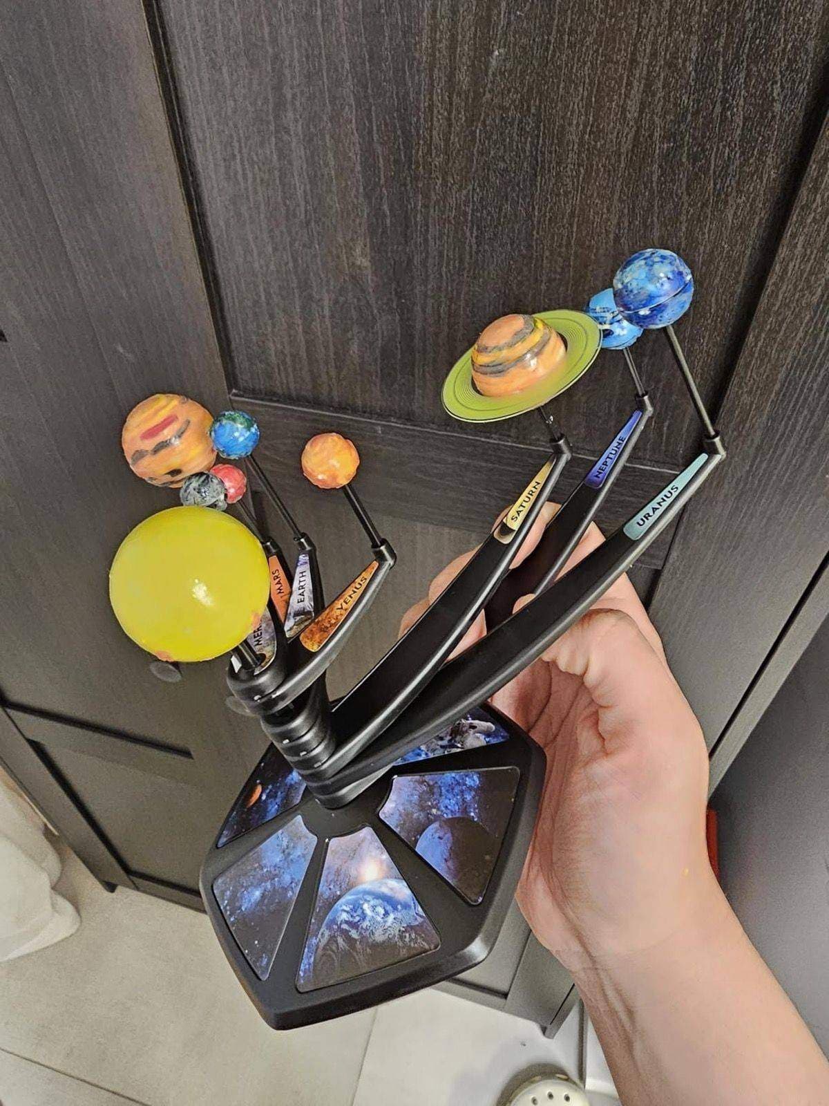 Hand holding the completed glowing solar system model