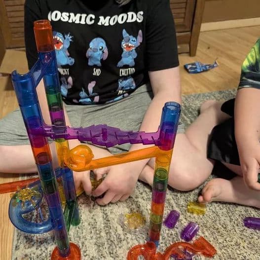 A completed marble run configuration with children visible in the background