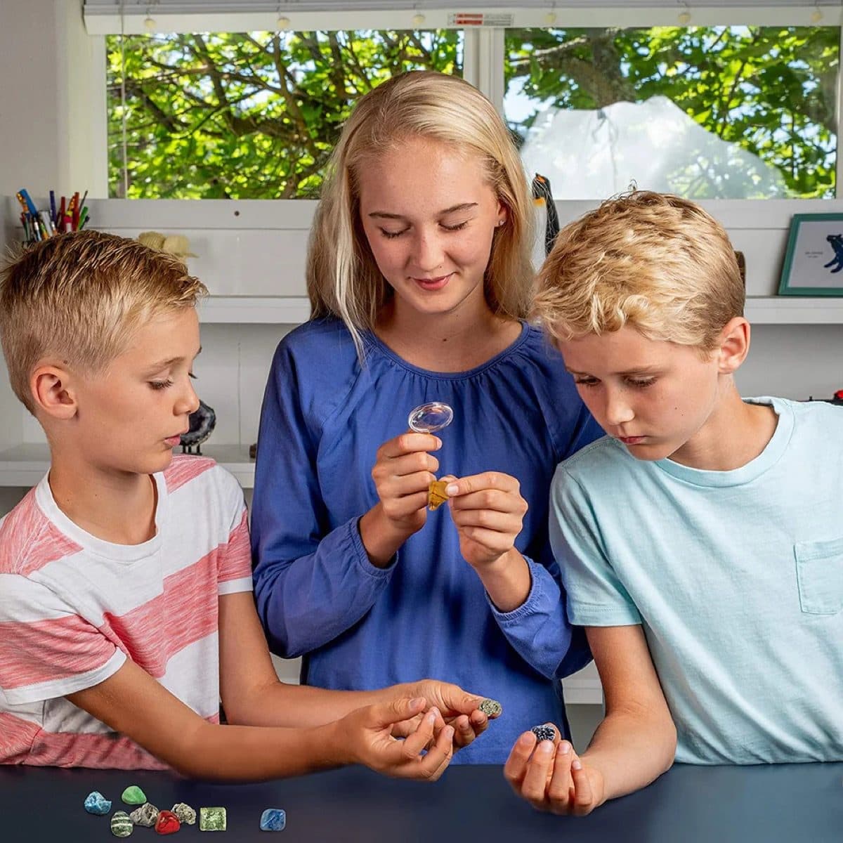 Three children examining rocks and minerals together outdoors