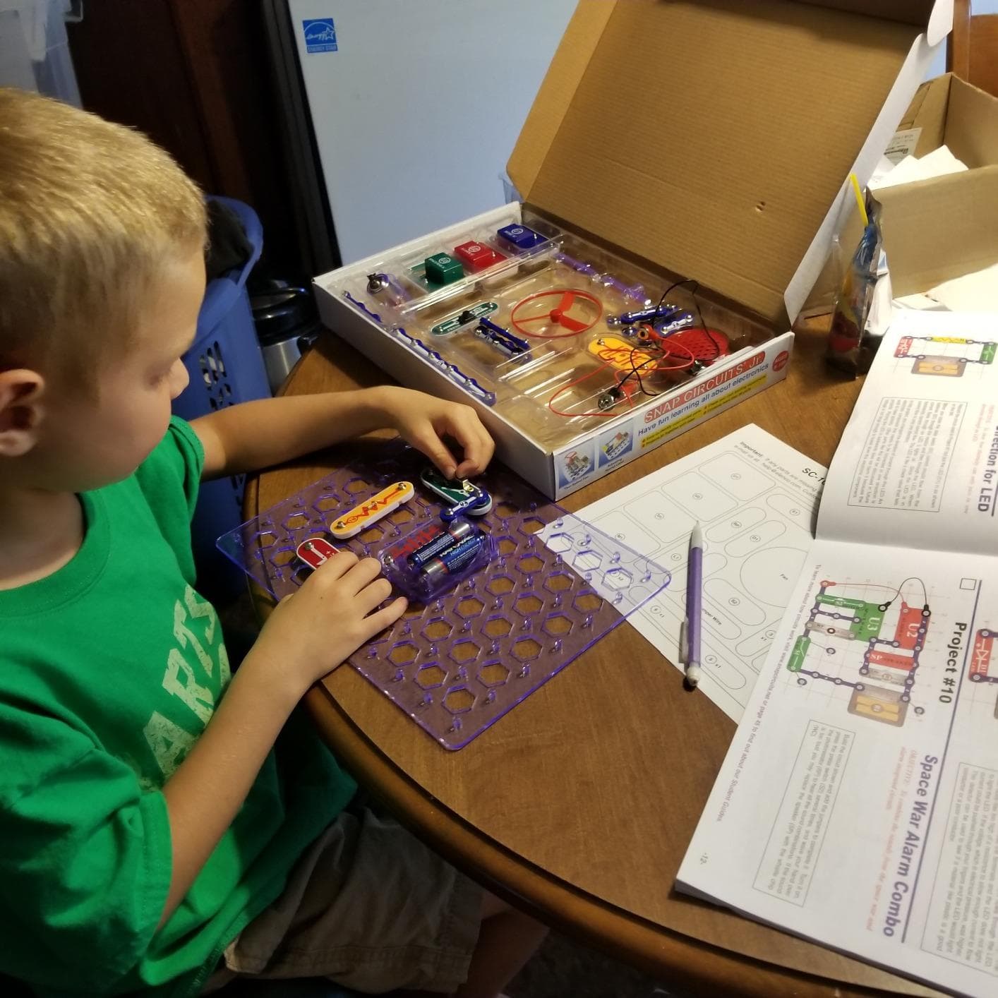 Child building circuits with components and box visible