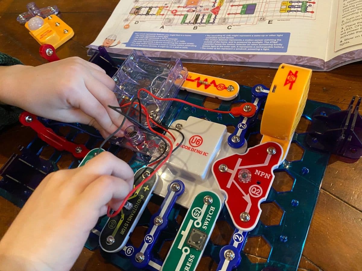 Hands snapping circuit pieces together on the board
